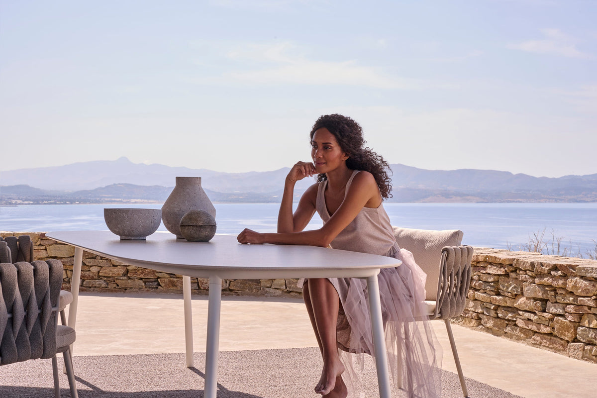 Tribù Tosca Esstisch mit ovaler Keramikplatte und Tosca Armlehnstuhl auf einer Terrasse über dem Meer