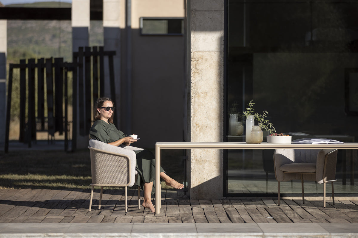 Todus Slide Essstuhl in Beige am Esstisch auf einer Holzterrasse