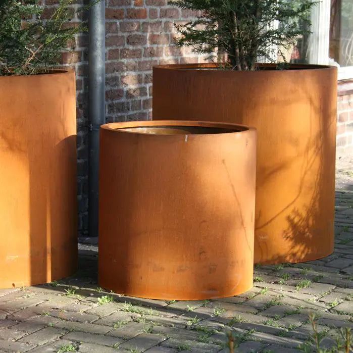 Das Pflanzgefäß Circum aus Cortenstahl bietet robustes Design und eine natürliche Rostschicht, die dem Garten eine warme, orangebraune Farbe verleiht. Das Gefäß ist wetterbeständig und langlebig. Es ist in verschiedenen Größen und Höhen erhältlich und sorgt für eine optimale Entwässerung dank der Entwässerungslöcher und Stützfüße.