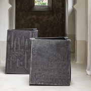 Atelier Vierkant Cube-S planter in handcrafted clay with textured surface, shown in a minimalist indoor architectural setting.