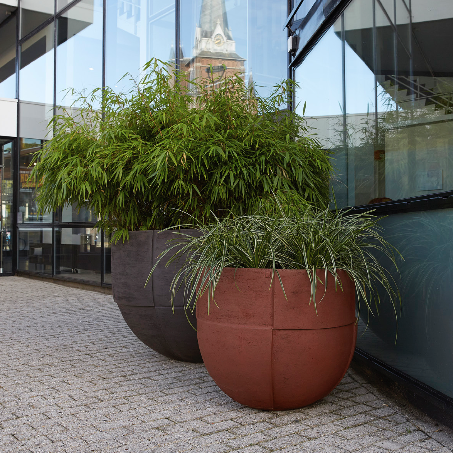 Das UO-Gefäß ist ein hochwertiges Terracotta-Pflanzgefäß mit einem schlanken, rund zulaufenden Fuß. Durch den schmalen Fuß gewinnt das große Gefäß an Leichtigkeit und bietet Solitärpflanzen ausreichend Wurzelraum. Die matte Oberfläche verleiht dem Gefäß eine natürliche, elegante Ausstrahlung, die gut mit verschiedenen Materialien harmoniert. Spezielle Brennvorgänge machen die Gefäße frostbeständig, sodass sie das ganze Jahr über im Freien genutzt werden können.