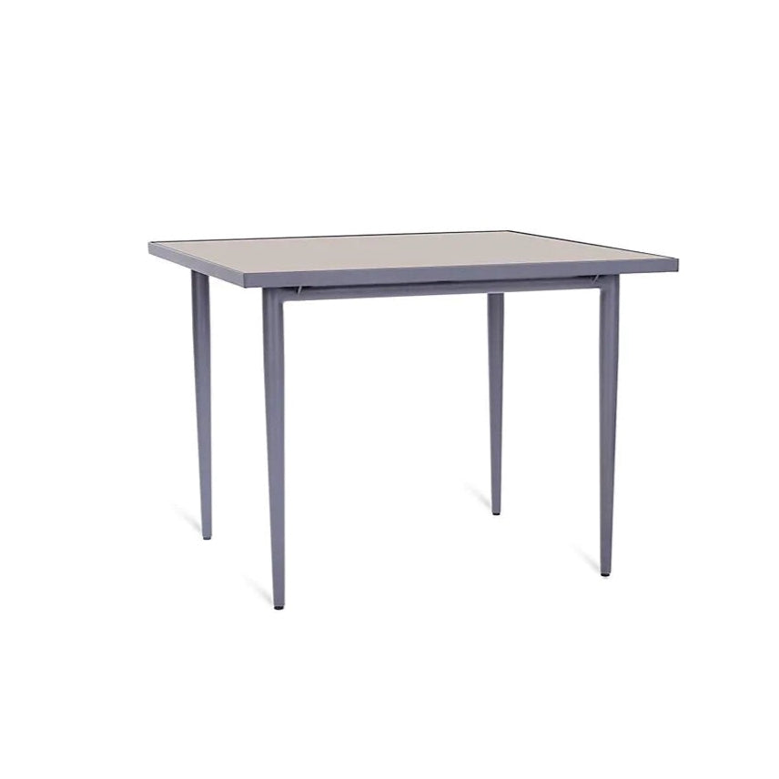 Ein runder Gartentisch, der UNOPIU Experience Esstisch, mit einer grauen Aluminium-Basis und einer beigen Feinsteinzeug-Tischplatte in Wüstenoptik. Der Tisch steht in einer Outdoor-Umgebung.