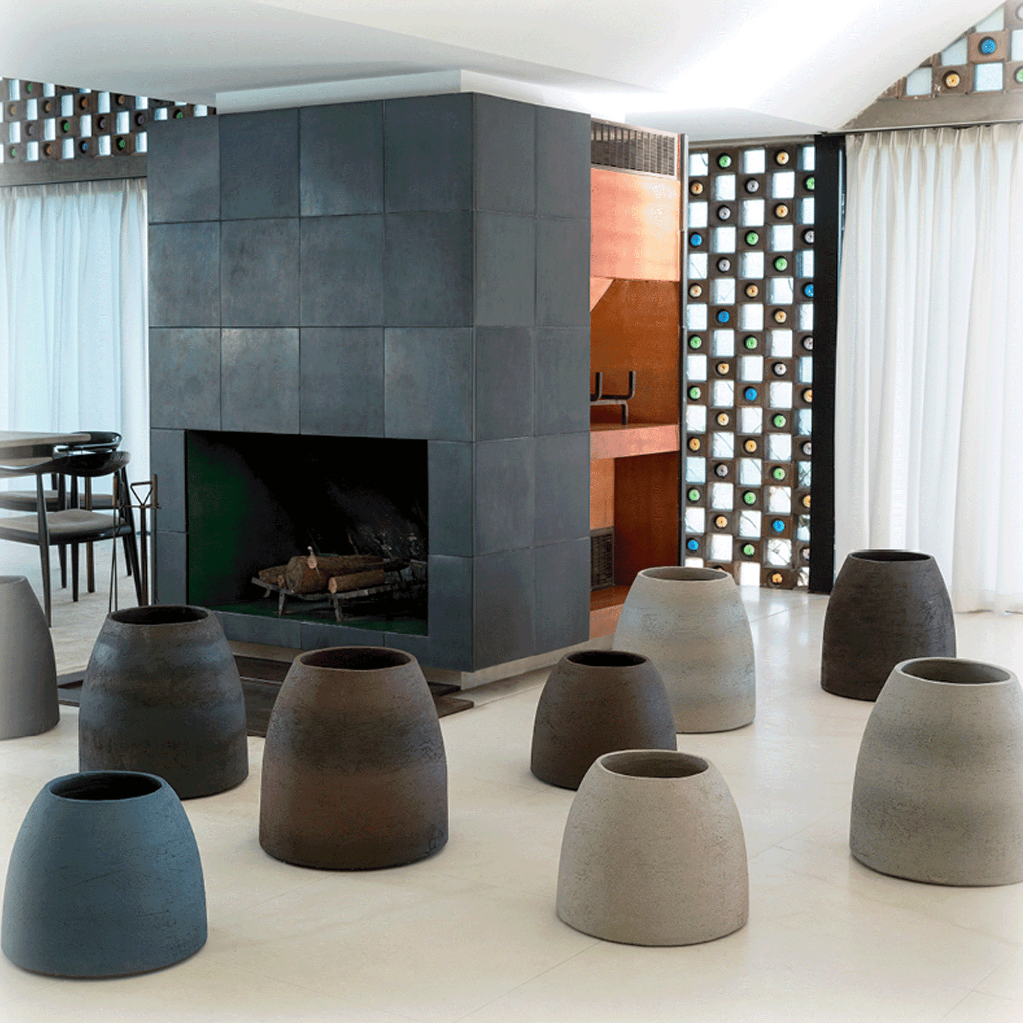 Diverse Atelier Vierkant Vasen TA30 und TA50 stehen vor einem gekacheltem Kamin. Rechts vom Kamin befindet sich ein Esstisch.