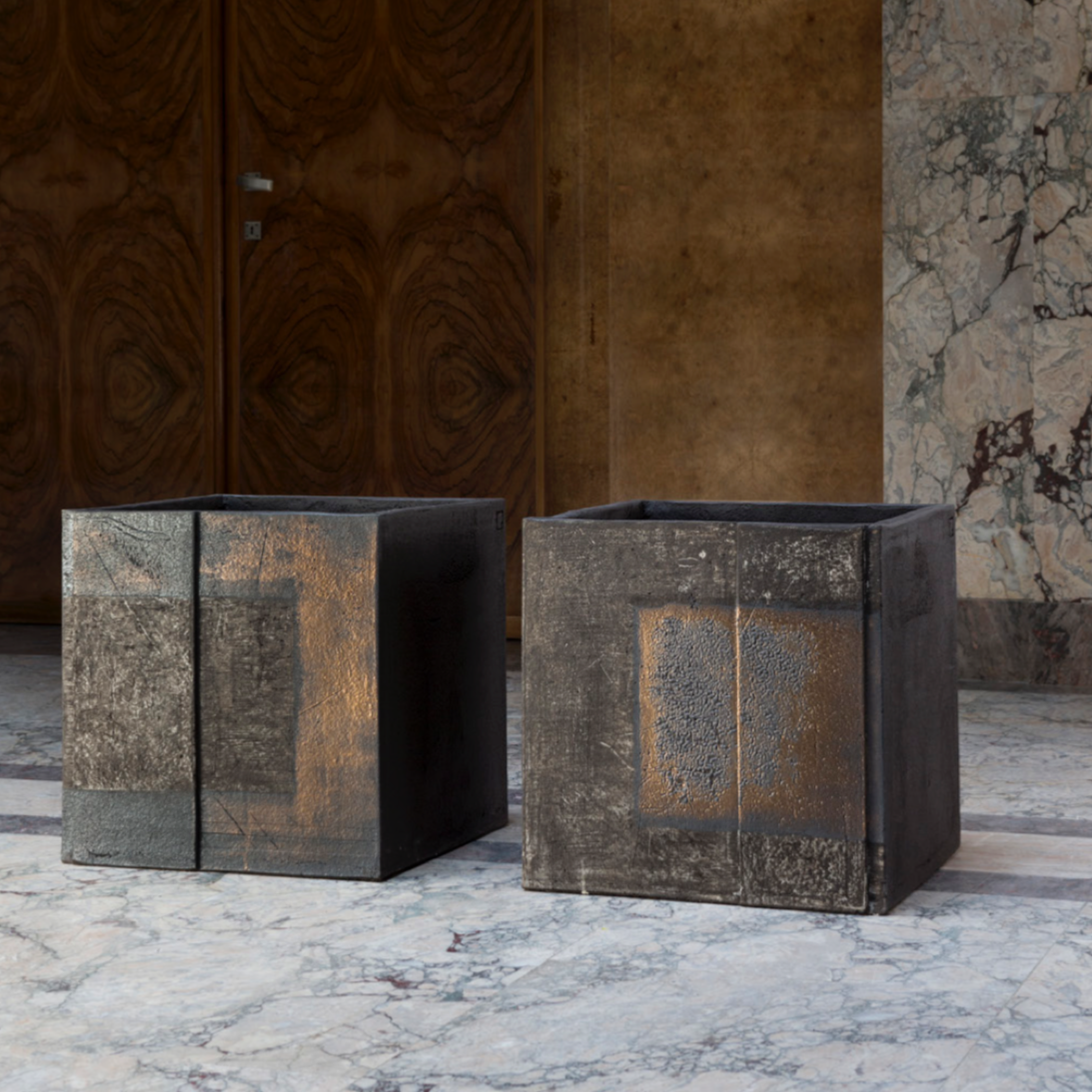 Das Atelier Vierkant BE4545 ist ein quadratisches Pflanzgefäß mit einer Breite, Tiefe und Höhe von 45 cm. Es besteht aus zwei Zwillingswürfeln in Schwarz-Anthrazit mit einem gold- und kupferfarbenen Muster.