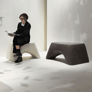 Atelier Vierkant Hocker HM90 in weiß und schwarz stehen in einem Museum. Auf dem weißen Terracotta Hocker sitz eine helle Frau welche schwarz gekleidet ist.