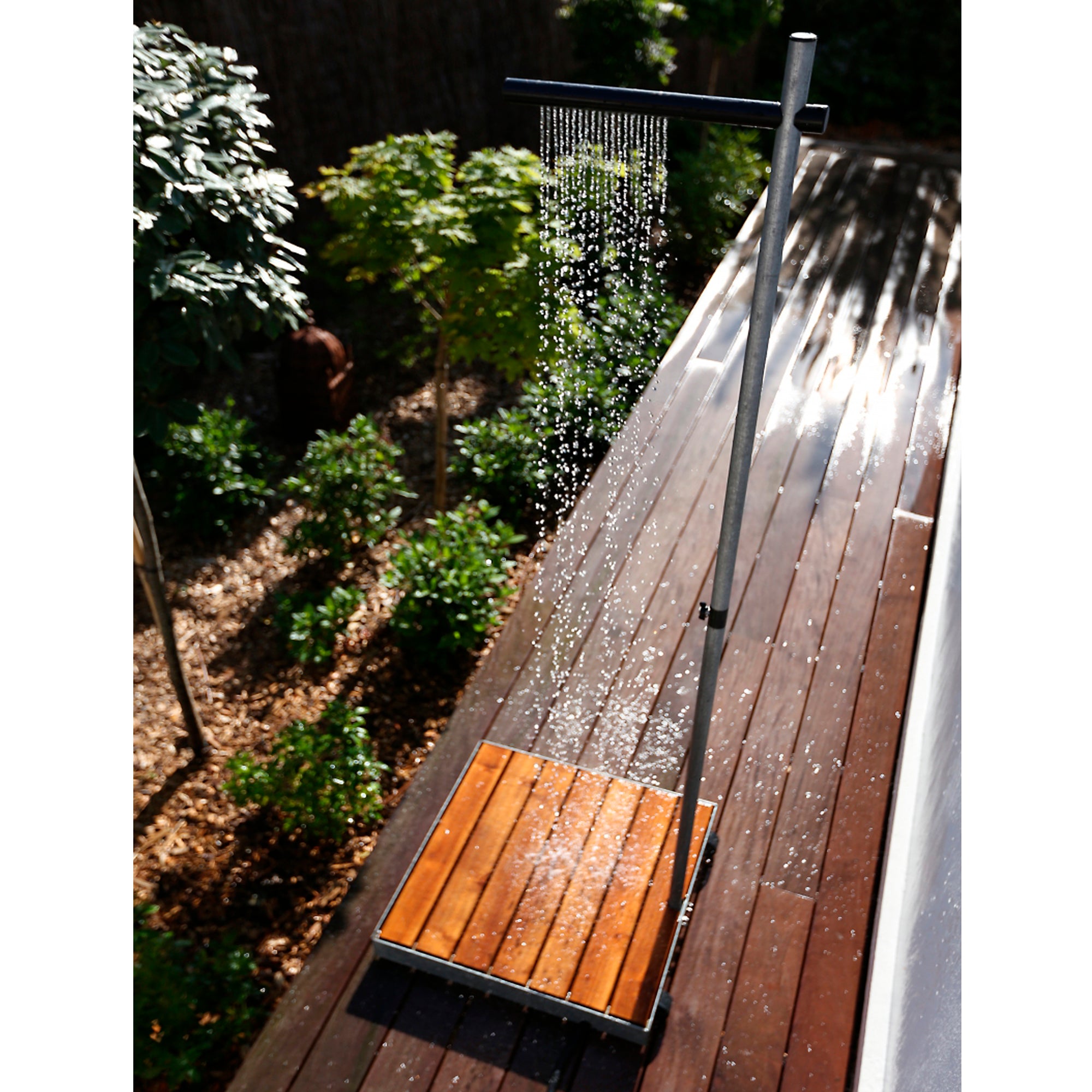 Tradewinds Garten-Dusche Cascade mit einem Nylon Sprühkopf steht auf einer Holzterrasse  im Garten.