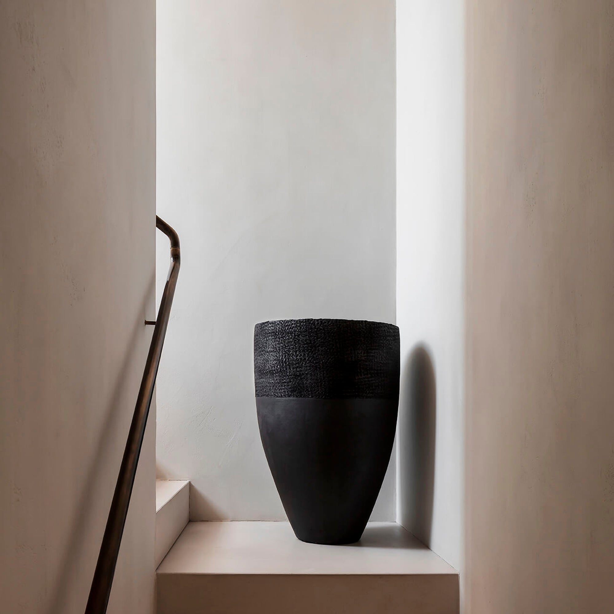 Domani Paris ist ein Blumenkübel in schwarz mit einem Ø40cm und einer Höhe von 120cm. Dieses Gefäß steht in einem hellen Treppenaufgang auf der mittleren Ebene.