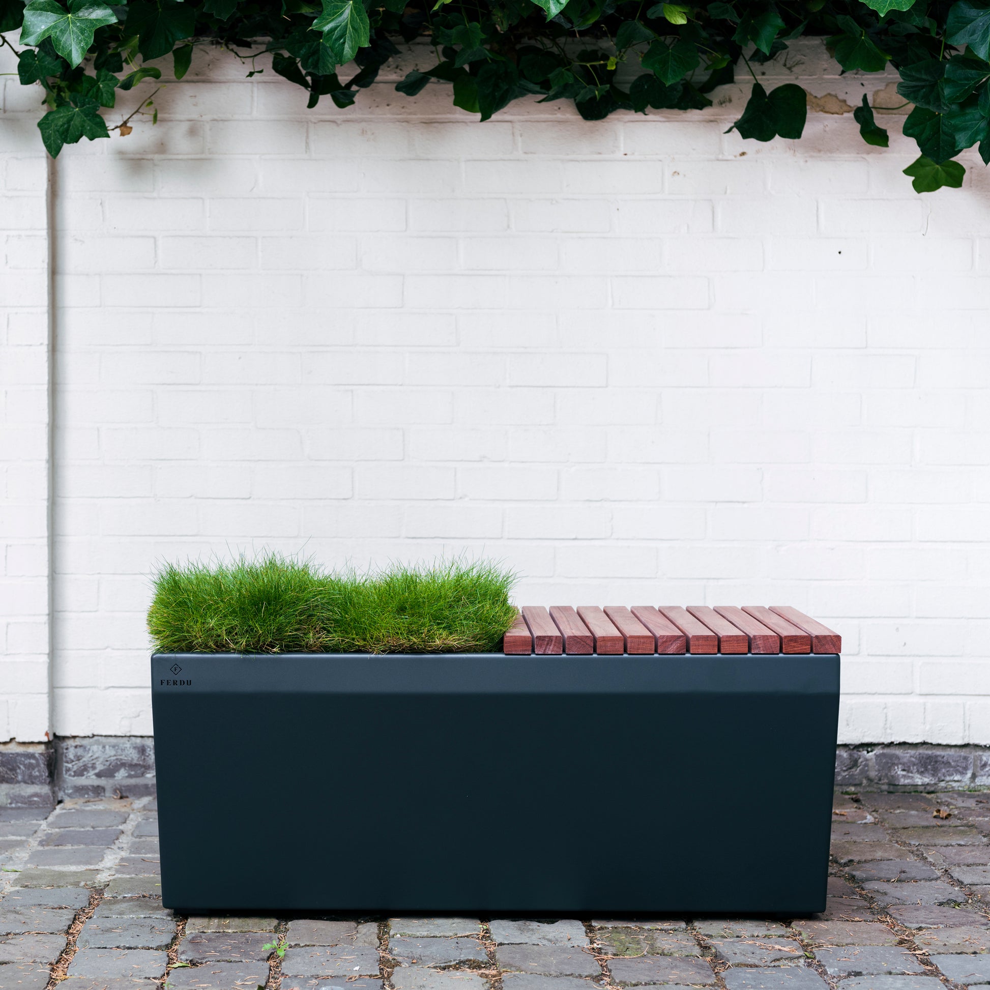 Pflanzengefäß Berta von FERDU von Hand in Belgien gefertigt. Dieses Gefäß ist aus Corten-Stahl und schwarz lackiert. Eine hälfte des Gefäßes ist eine Sitzfläche aus Holz.