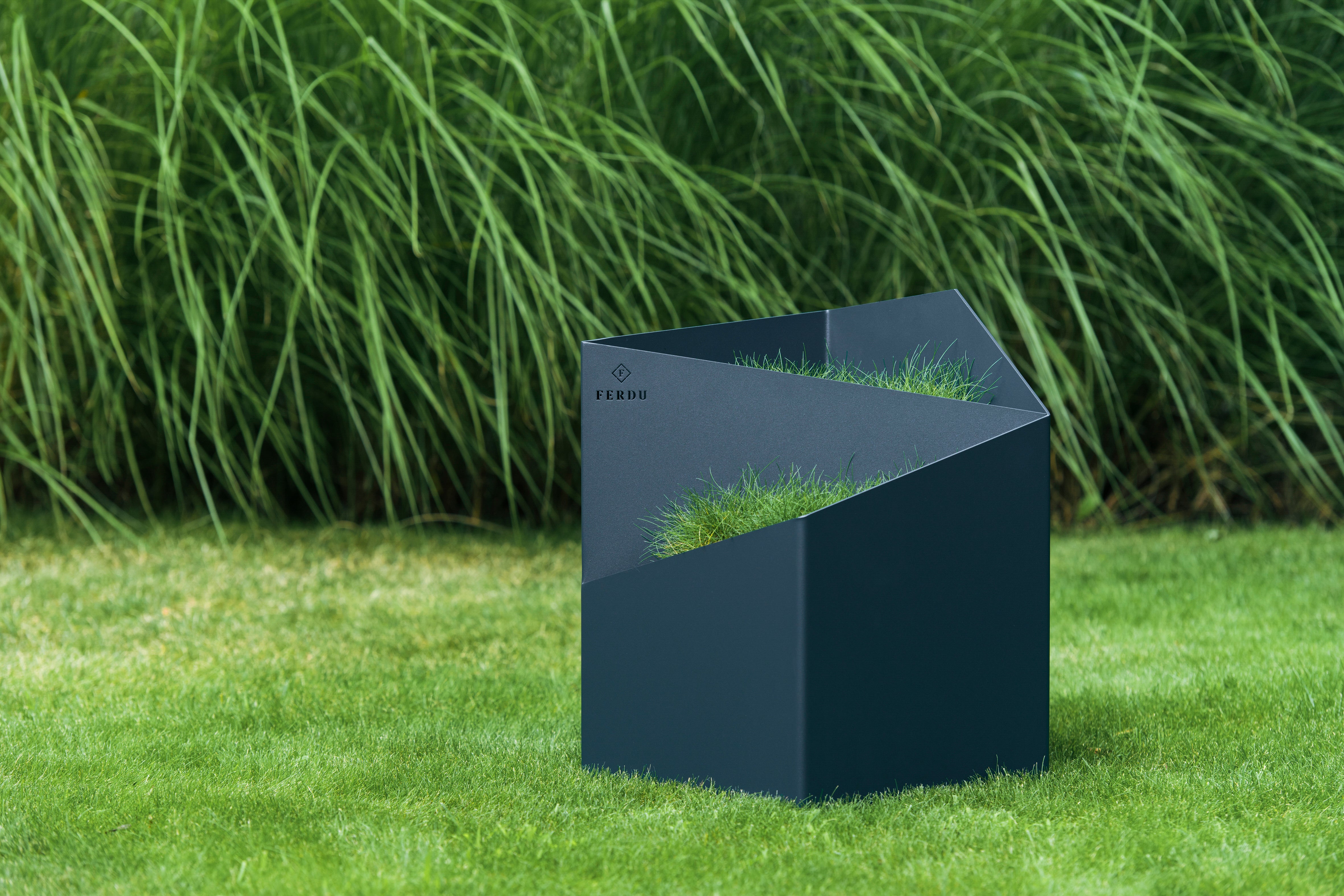 FERDU Gefaess Doblu aus CORTENSTAHL black lackiert auf einem Rasen. Im Hintergrund sind Gräser gepflanzt.