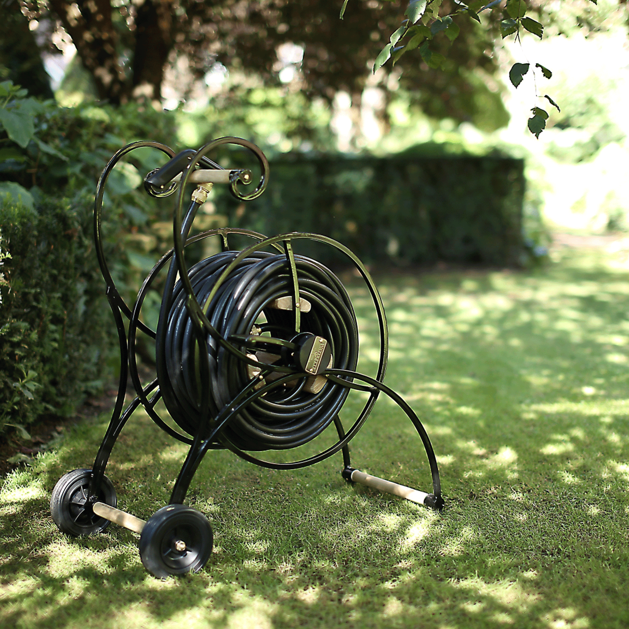 Romantischer Gartenschlauchwagen De Tuun in schwarz steht vor einer Hecke im Rasen.