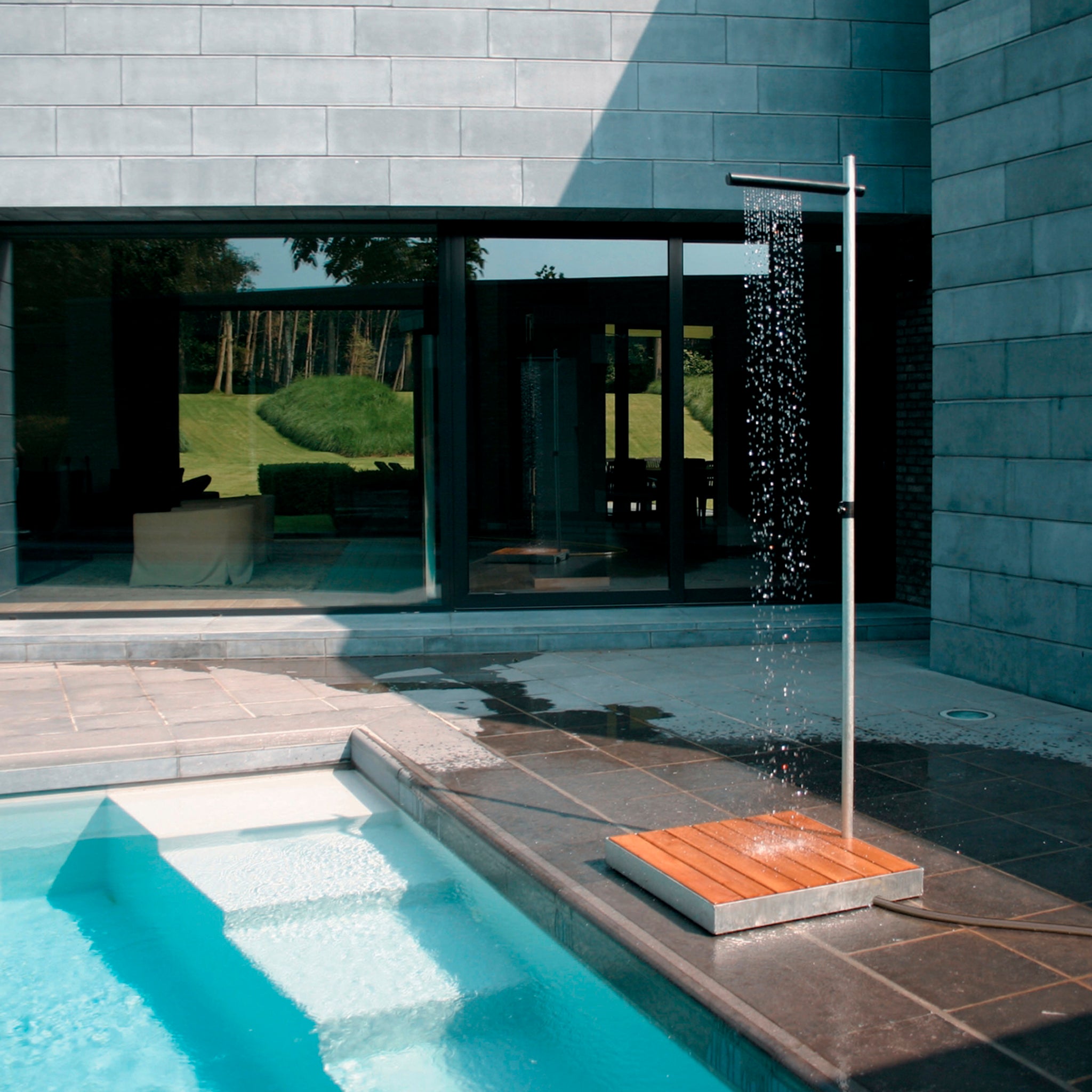 Minimalistische Außendusche steht am Poolrand. Die Gartendusche  sprüht wie eine Gardine. Der Sprühkopf ist aus schwarzem Nylon.