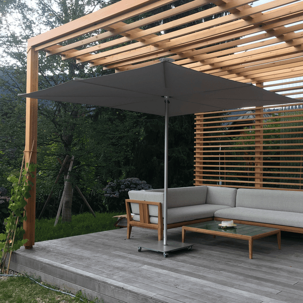 Umbrosa Sonnenschirm Infina 3x3m in taupe. Der Sonnenschirm steht unter einem Holzpavillon.