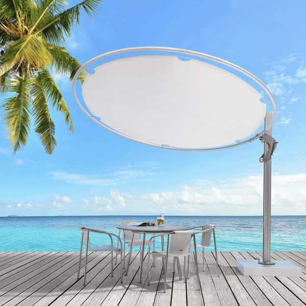 Umbrosa Sonnenschirm Eclipsum in weiss am Strand in der Karibik auf einer Teakholz Terrasse mit einem Bistrotisch und 4 weißen Stühlen.