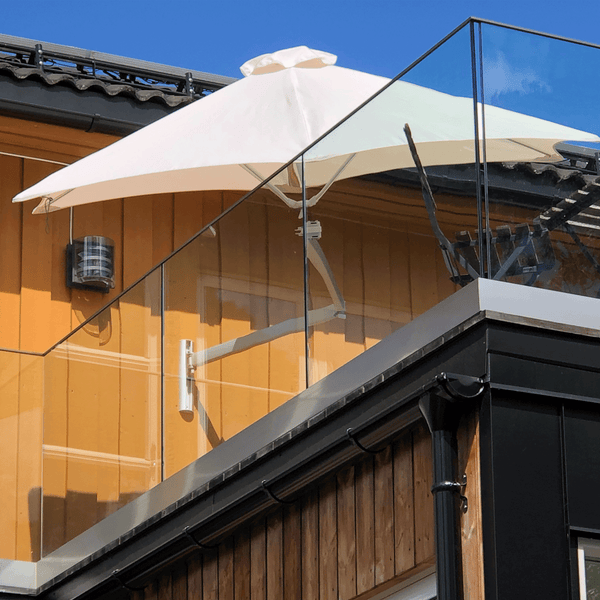 Umbrosa Sonnenschirm Paraflex in weiß an einer gelben Hauswand auf dem Balkon.
