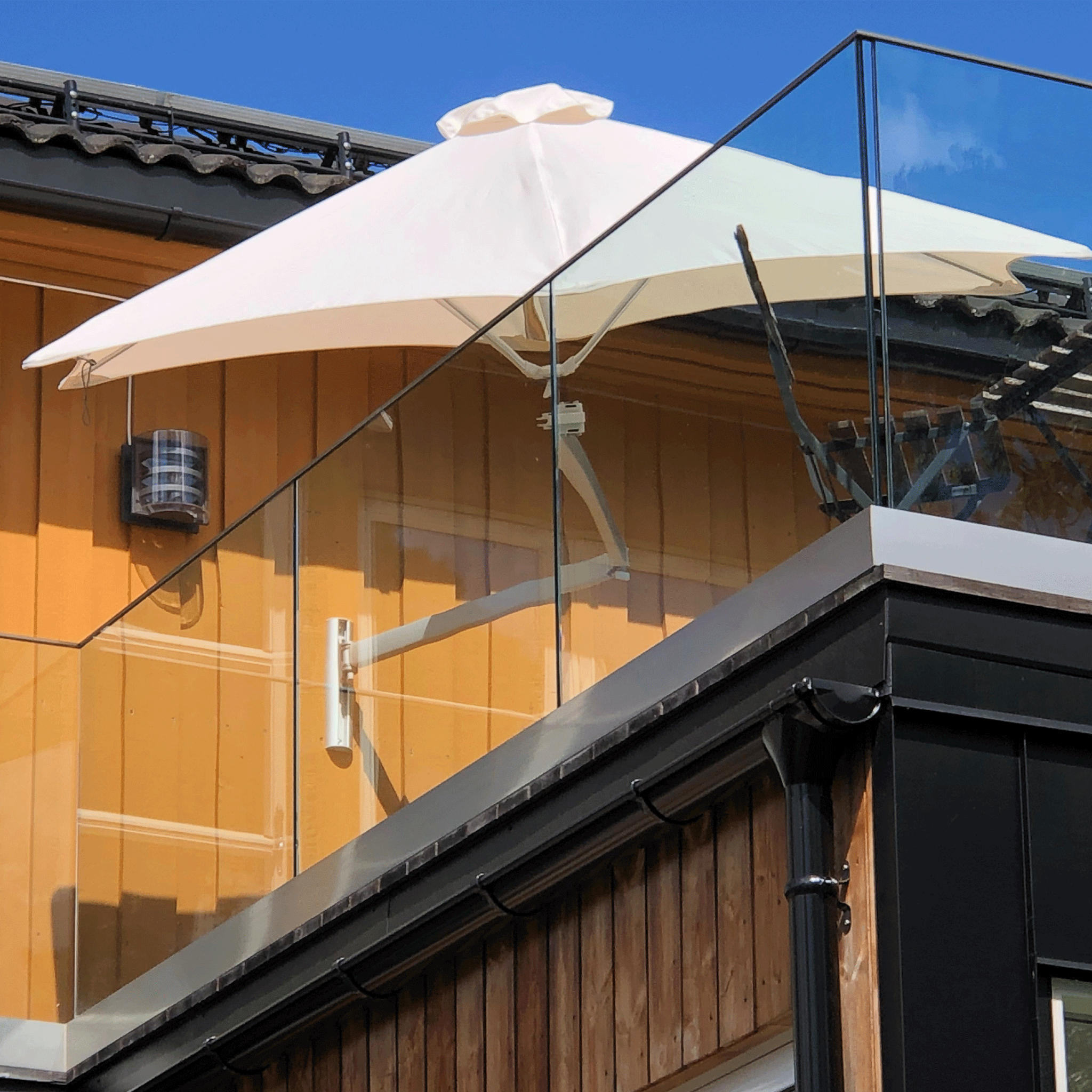 Umbrosa Sonnenschirm Paraflex in weiß an einer gelben Hauswand auf dem Balkon.