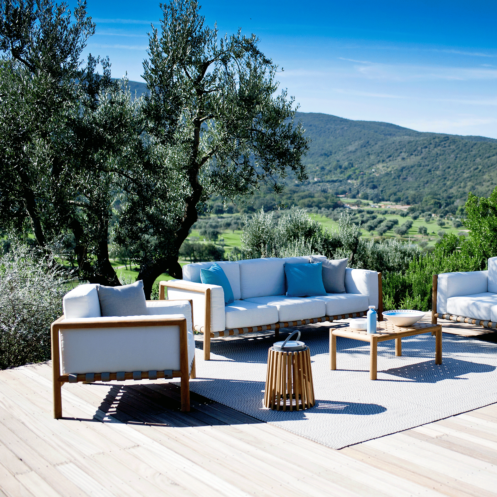 Unopiu Sessel Pevero steht vor dem Pevero 3 Setzer Sofa auf einer Terrasse in der Toscana.