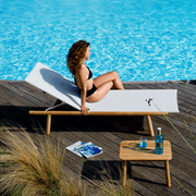 Sonnenliege Pevero von Unopiu am Hotelpool. Auf der Sonnenliege sitz eine Junge Frau mit leicht gelockten haaren im schwarzen Bikini.