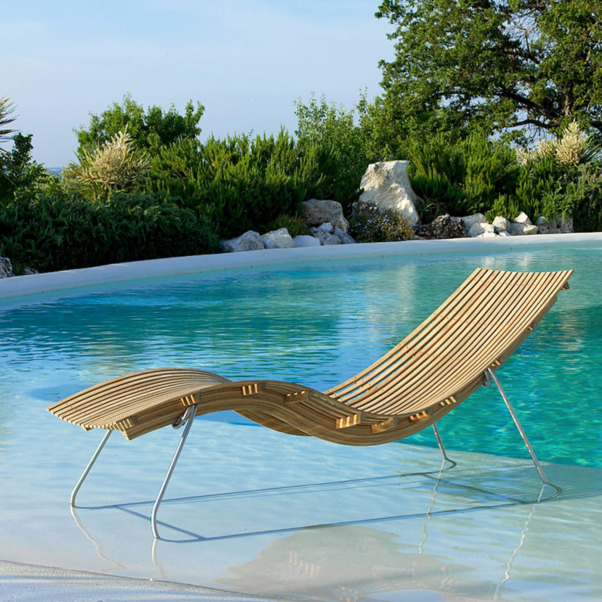 Eine Unopiu Liege für den Sommer steht im Pool. Die Teakholz Sun Lounger ist perfekt für jeden Garten.