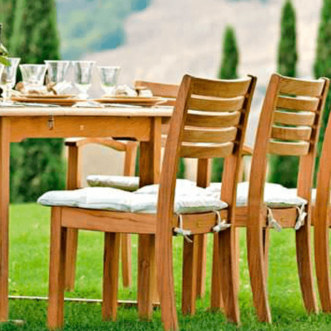 Diese 3 Unopiu Stühle Chelsea sind aus Teakholz und stehen im Garten an einem Teakholz Esstisch. Von den Gartenstühlen aus haben Sie einen schönen Blick auf die Pinien.