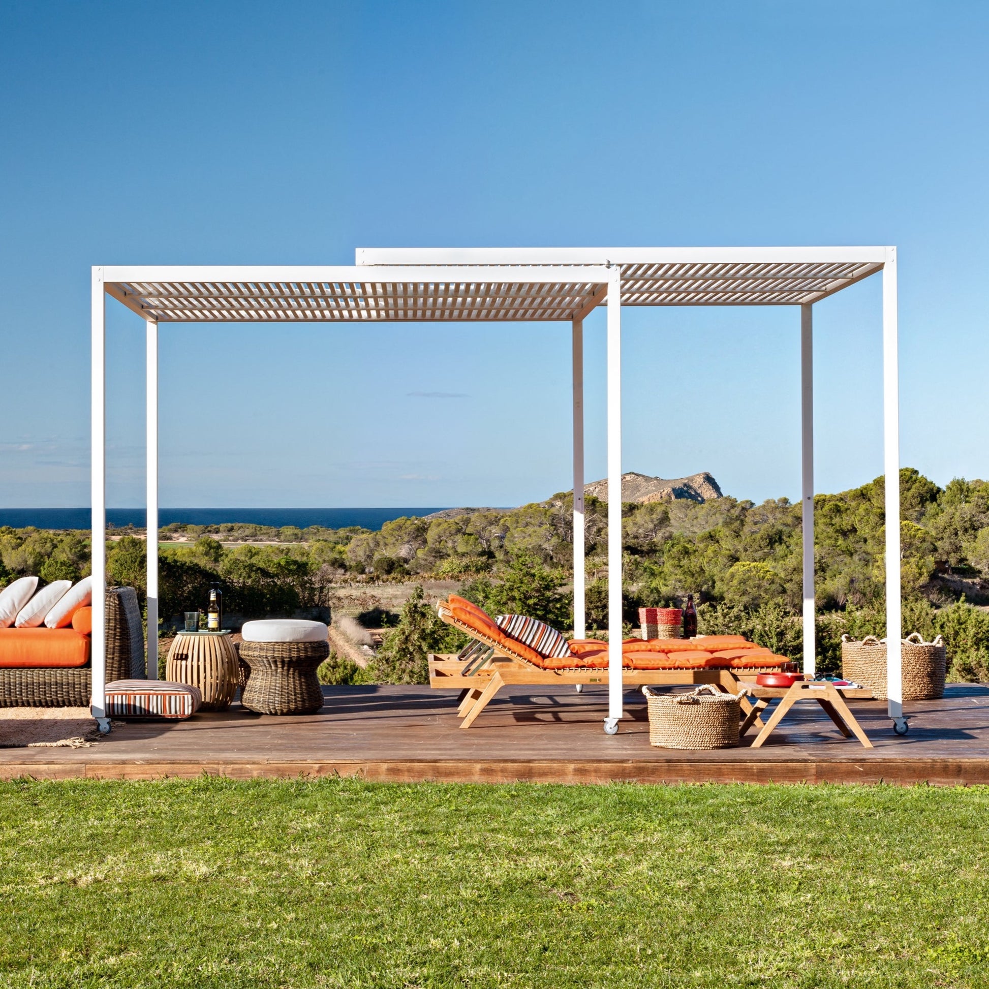 weiße Unopiu bewegliche Pergola Shibuya auf Rollen. Unter der Pergola stehen 2 Synthesis Liegen aus Teakholz mit orangenen Auflagen.