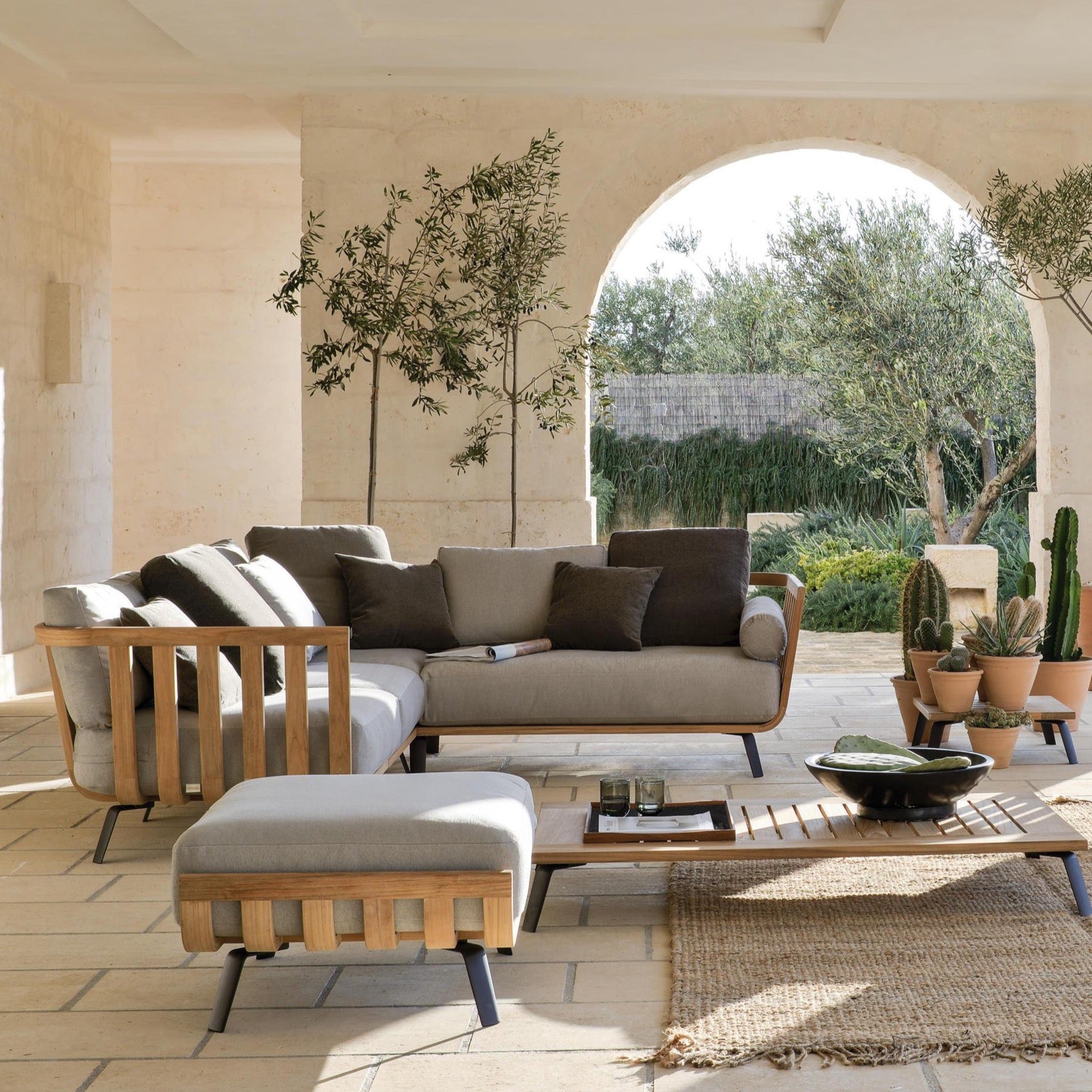 Unopiu Welkom aus Teakholz mit grauen Polstern und braunen Decokissen.